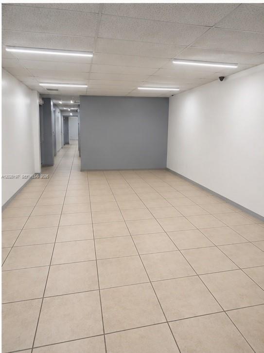 An empty office space features beige tile flooring, white walls, and a gray accent wall — 5555 NW 74th Ave # 5555, Miami FL 33166, MIAMI, FL