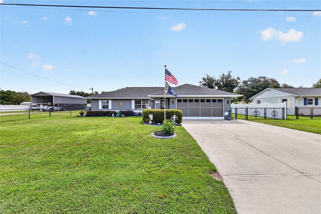 A single-story gray house with a garage, a concrete driveway, and an American flag — 11631 SE 84TH AVENUE, BELLEVIEW, FL