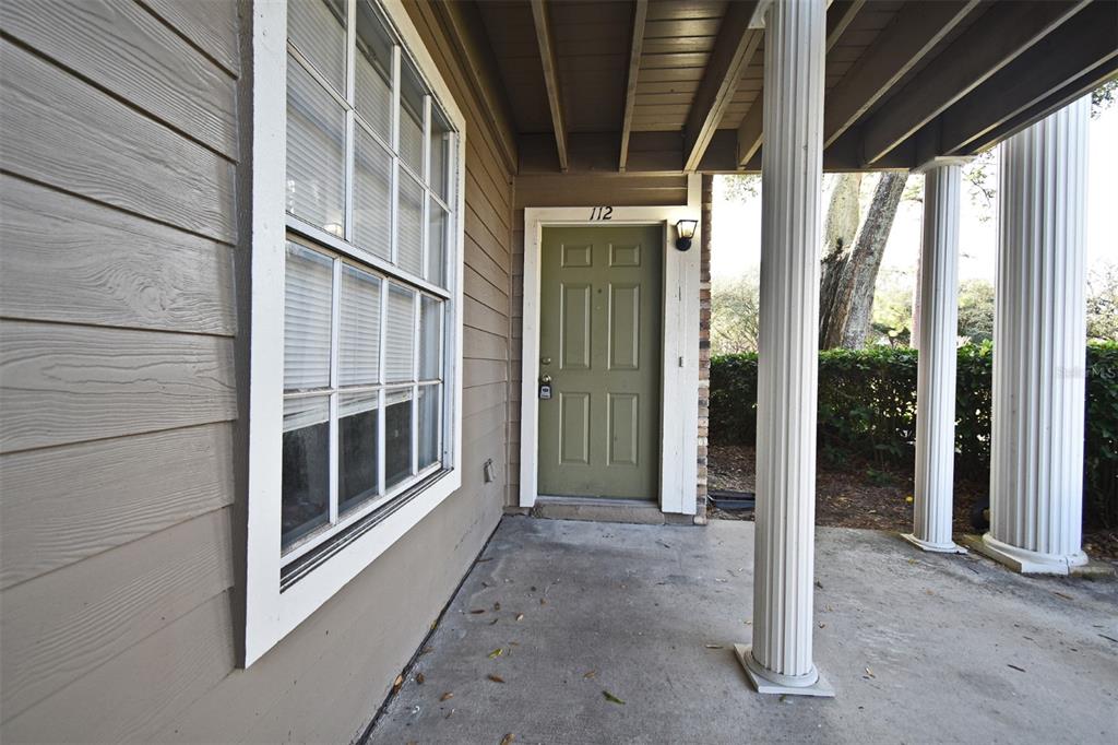 A covered porch with columns leads to a green front door labeled 112 — 144 RESERVE CIRCLE UNIT 112, OVIEDO, FL