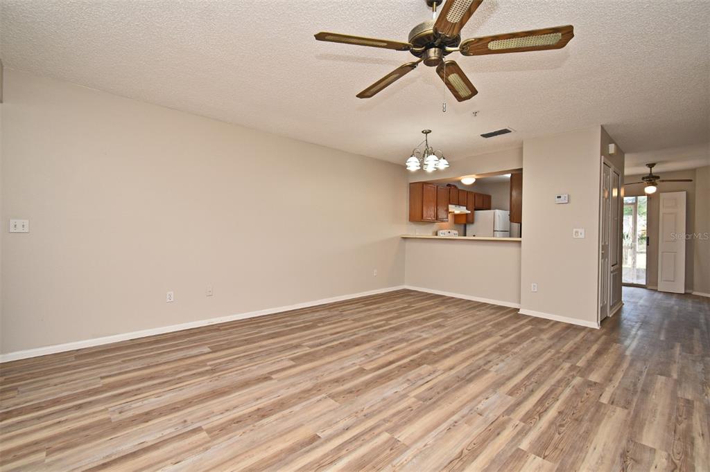 An open-concept living room features light wood-look flooring, a ceiling fan, and a kitchen pass-through — 144 RESERVE CIRCLE UNIT 112, OVIEDO, FL