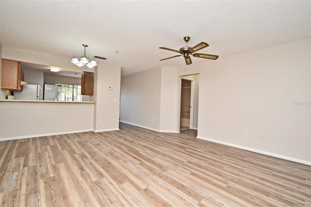 An open-concept living area features light wood-look flooring, a ceiling fan, and a kitchen pass-through — 144 RESERVE CIRCLE UNIT 112, OVIEDO, FL