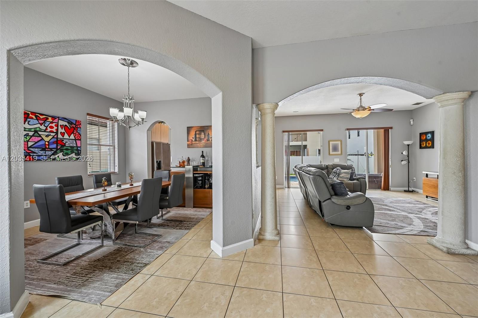 An open-concept dining room and living room with arched entryways and tiled flooring — 18159 NW 90th Ave, Hialeah FL 33018, HIALEAH, FL