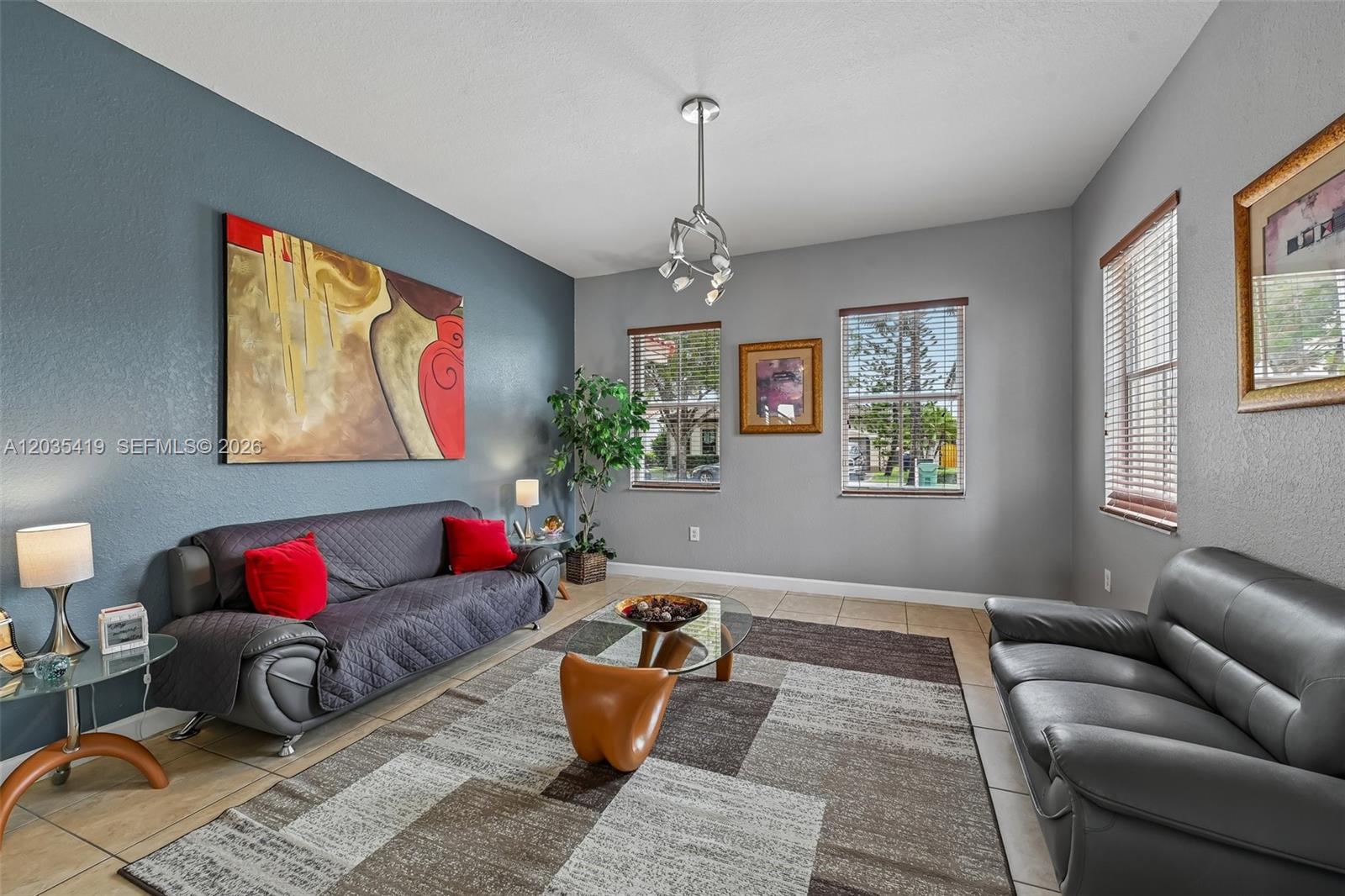 A living room features gray walls, a blue accent wall, tile floors, and two sofas — 18159 NW 90th Ave, Hialeah FL 33018, HIALEAH, FL
