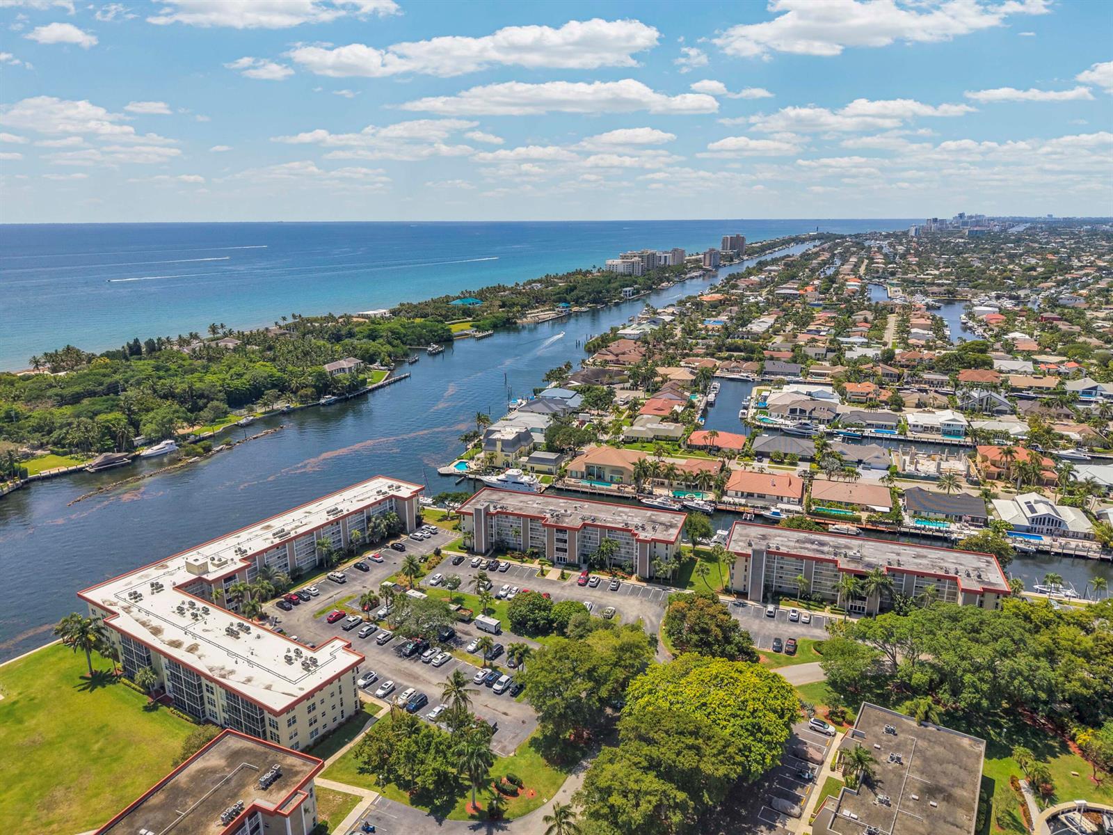 An aerial view shows multi-story apartment buildings with parking lots situated along a coastal waterway — 3050 NE 48th Court # 305, Lighthouse Point FL 33064, LIGHTHOUSE POINT, FL