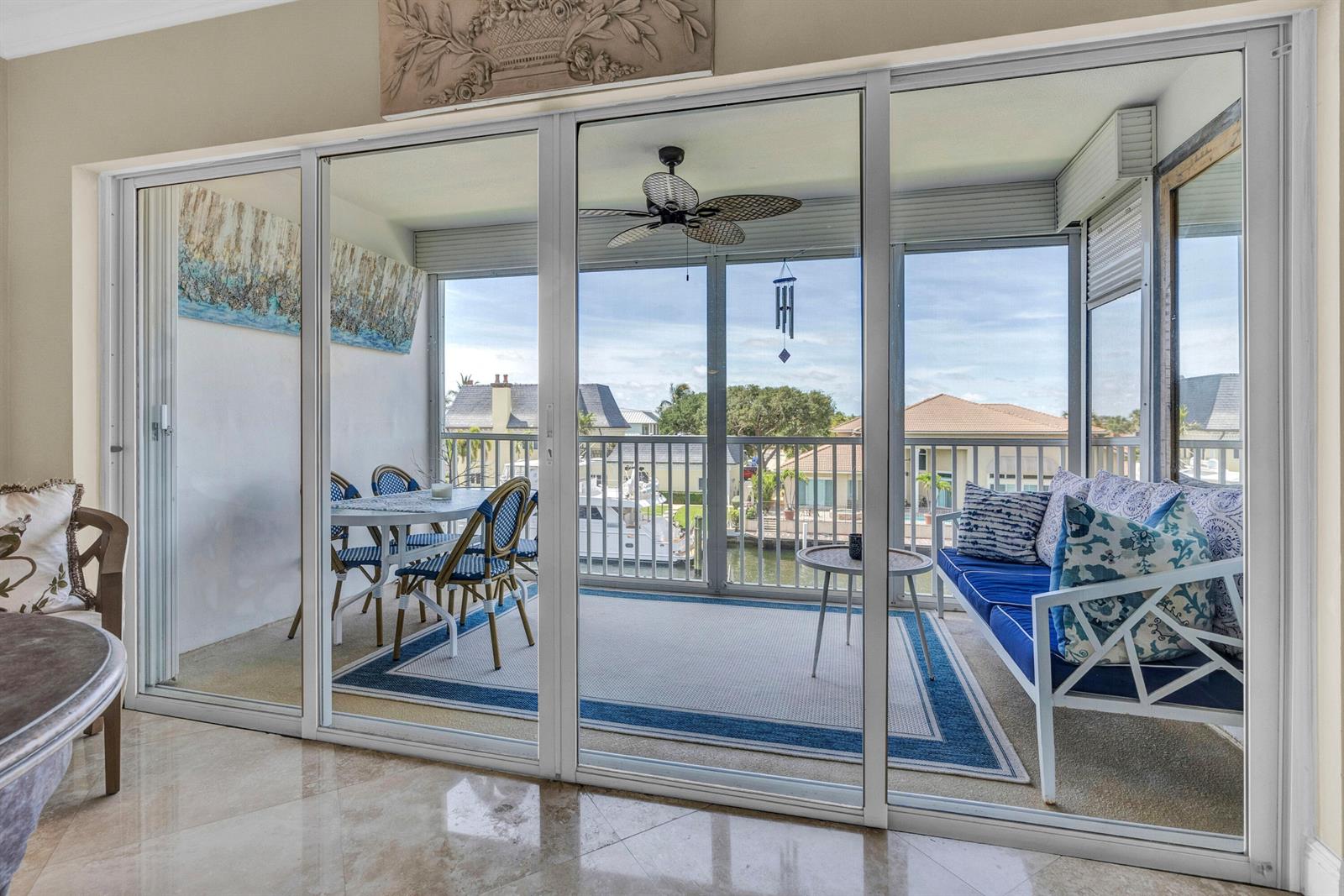A sunroom with a dining set and sofa overlooks a canal with docked boats — 3050 NE 48th Court # 305, Lighthouse Point FL 33064, LIGHTHOUSE POINT, FL