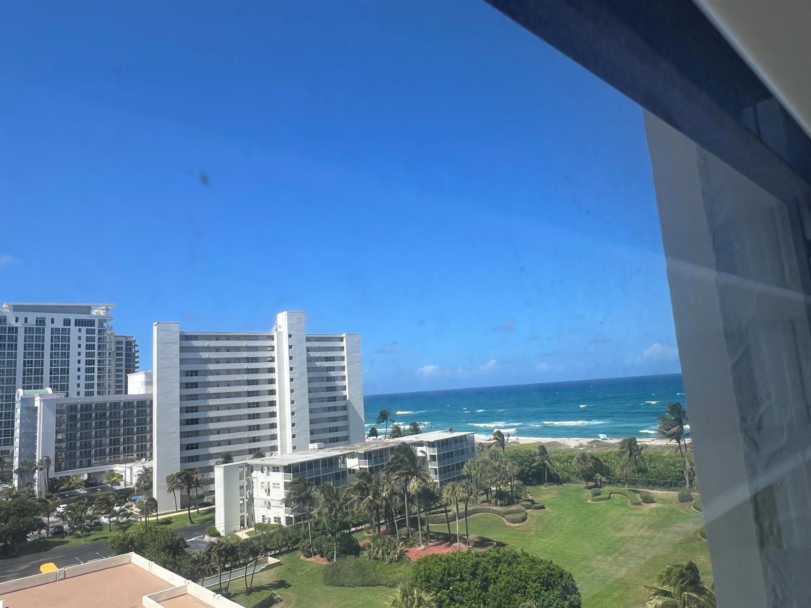 An elevated view of a beach, ocean, and white high-rise buildings from a window — 3400 N Ocean Drive # 803, Riviera Beach FL 33404, RIVIERA BEACH, FL
