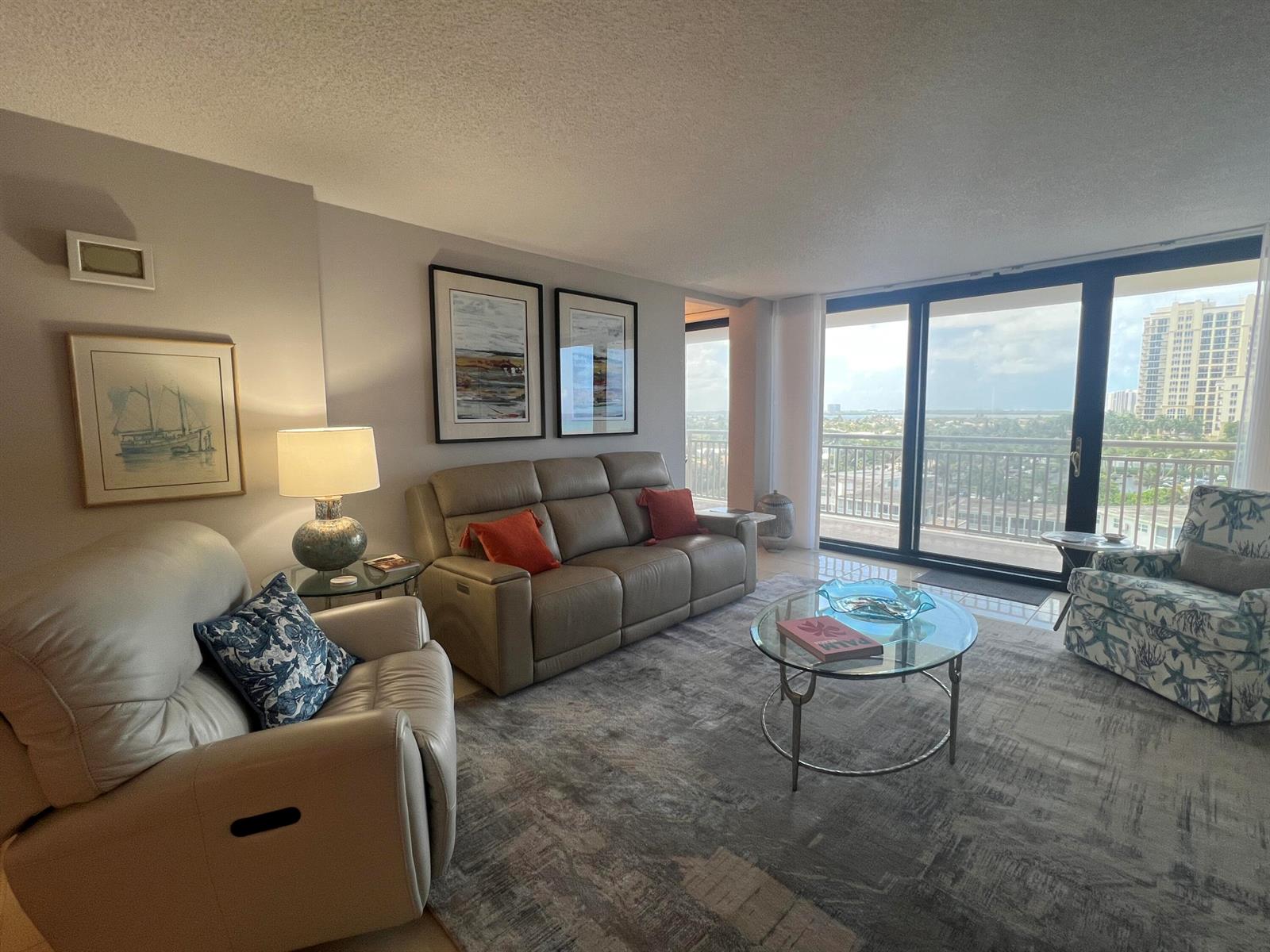 A living room features a leather sofa, two armchairs, a glass coffee table, and balcony views — 3400 N Ocean Drive # 803, Riviera Beach FL 33404, RIVIERA BEACH, FL