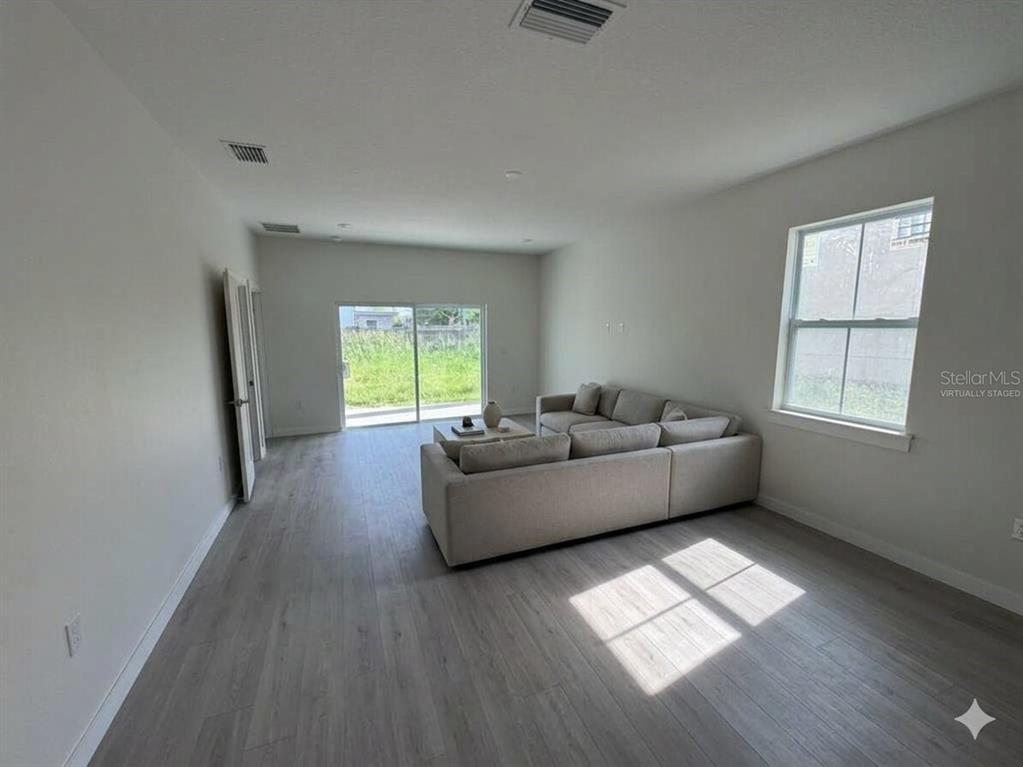 A living room features light wood-look flooring, a sectional sofa, and a sliding glass door — 601 W MILLER STREET, ORLANDO, FL