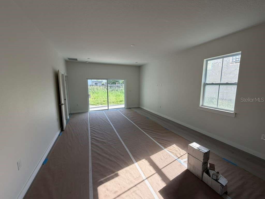 An empty room with light-colored walls, wood-look flooring, a sliding glass door, and one window — 601 W MILLER STREET, ORLANDO, FL