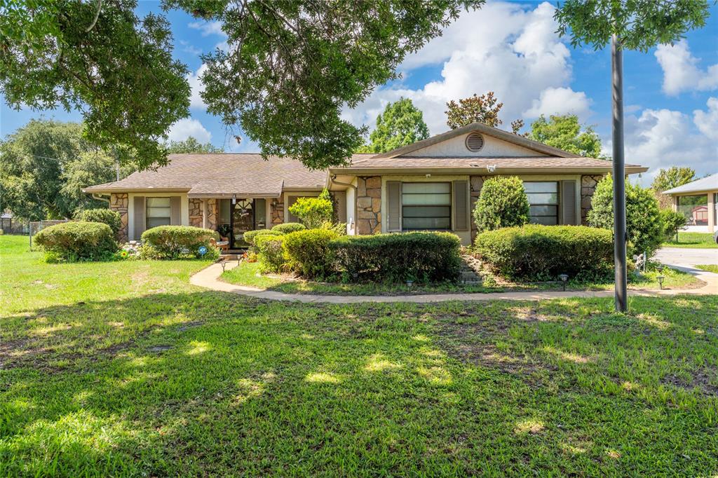 A single-story house with a stone facade, brown roof, and landscaped front yard — 2590 BORINQUEN DRIVE, KISSIMMEE, FL