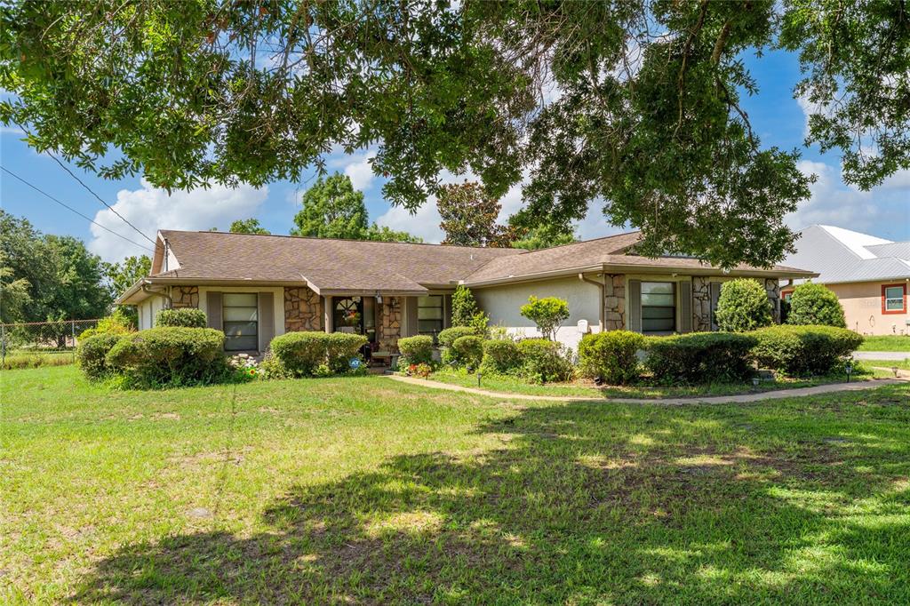 A single-story house with a stone facade, brown roof, and landscaped front yard — 2590 BORINQUEN DRIVE, KISSIMMEE, FL