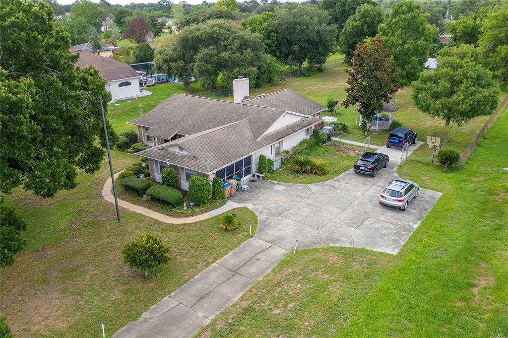 An aerial view shows a single-story house with a concrete driveway and a large yard — 2590 BORINQUEN DRIVE, KISSIMMEE, FL