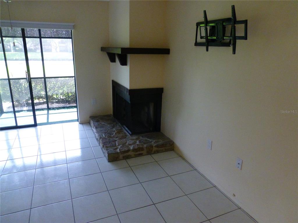 A living room features a stone-hearth fireplace, a dark wood mantel, and sliding glass doors — 119 LAKESIDE DRIVE UNIT 119, OLDSMAR, FL