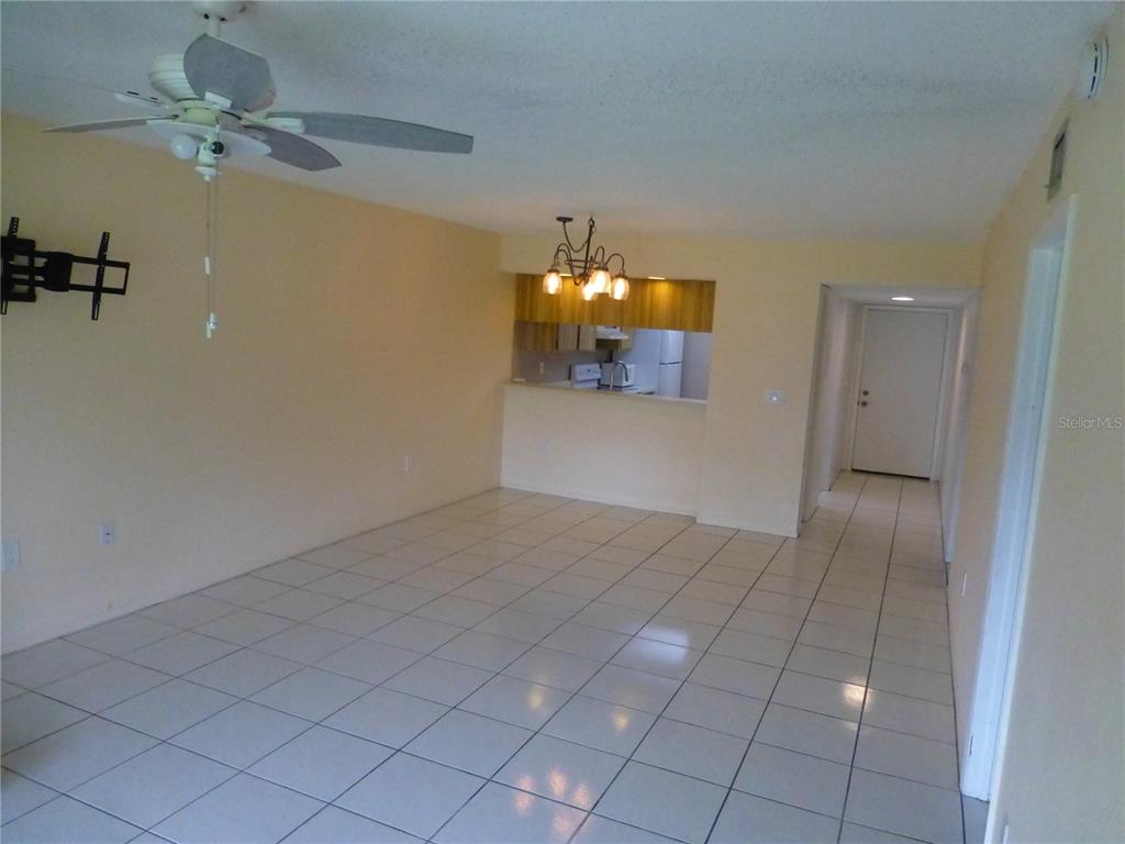 A living room with light-colored tile flooring, a ceiling fan, and an open kitchen pass-through — 119 LAKESIDE DRIVE UNIT 119, OLDSMAR, FL