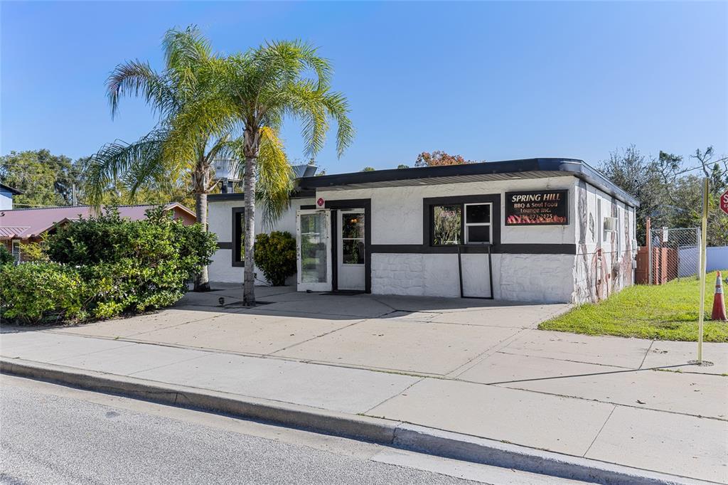 A single-story commercial building with a white stucco exterior and a palm tree out front — 905 S ADELLE AVENUE, DELAND, FL