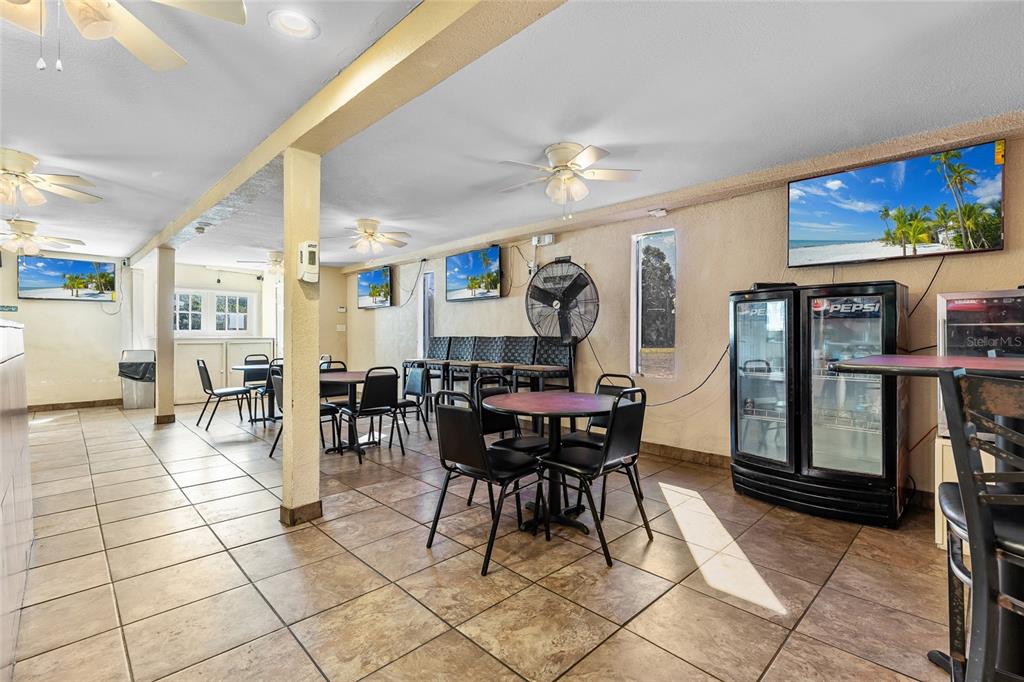 A commercial dining area features tiled floors, multiple ceiling fans, tables, chairs, and televisions — 905 S ADELLE AVENUE, DELAND, FL