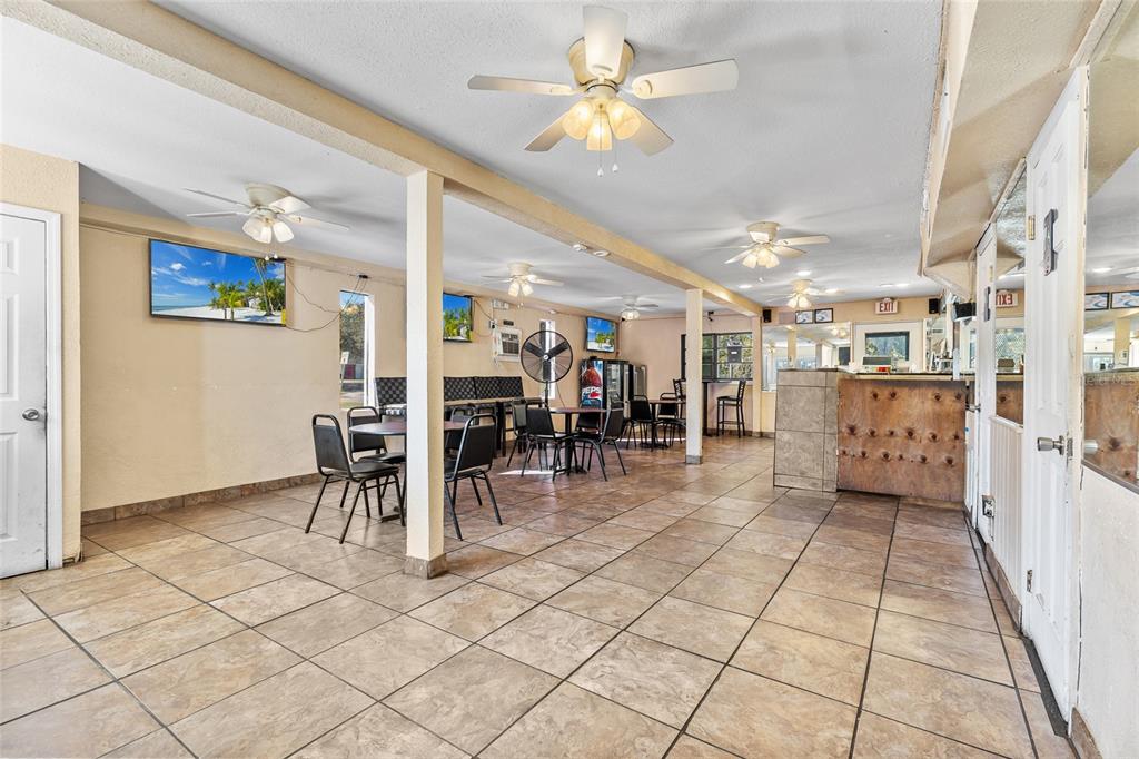 A commercial dining area features tile flooring, multiple ceiling fans, and a wooden service counter — 905 S ADELLE AVENUE, DELAND, FL