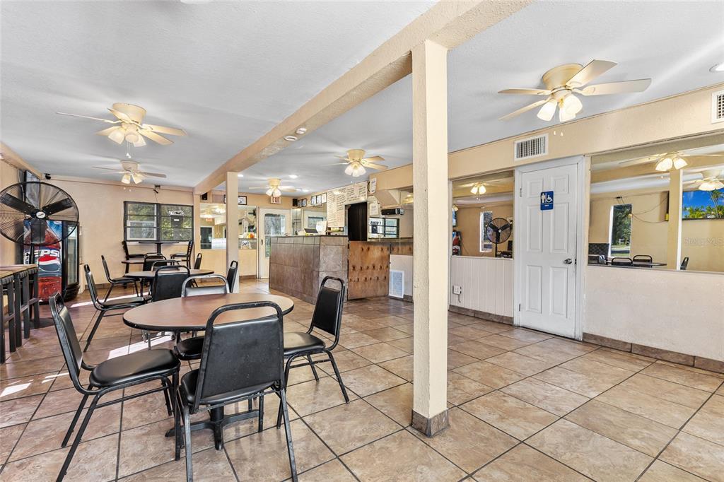 A restaurant dining area features tiled floors, multiple ceiling fans, and a central service counter — 905 S ADELLE AVENUE, DELAND, FL