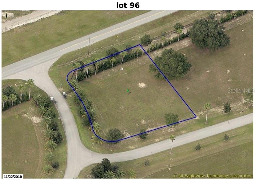 An aerial view shows a vacant, grass-covered lot outlined in blue near a paved road — 17200 ROYAL PALM DRIVE, GROVELAND, FL
