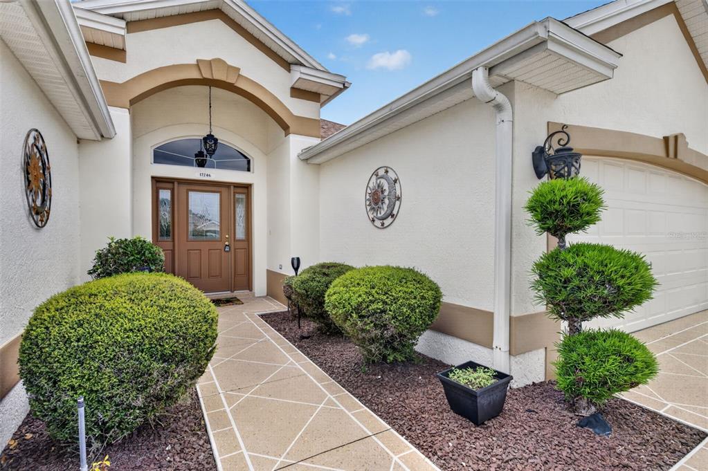 A front entryway features a brown door, a paved walkway, and manicured landscaping — 17246 SE 85TH WILLOWICK CIRCLE, THE VILLAGES, FL