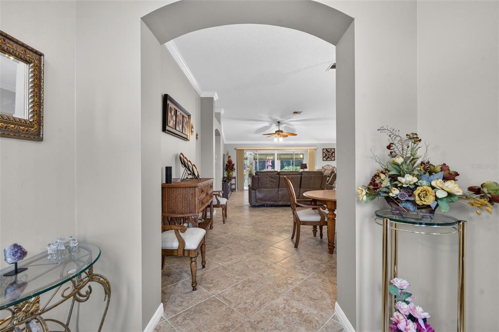 A view through an arched doorway into a living room with tile flooring — 17246 SE 85TH WILLOWICK CIRCLE, THE VILLAGES, FL