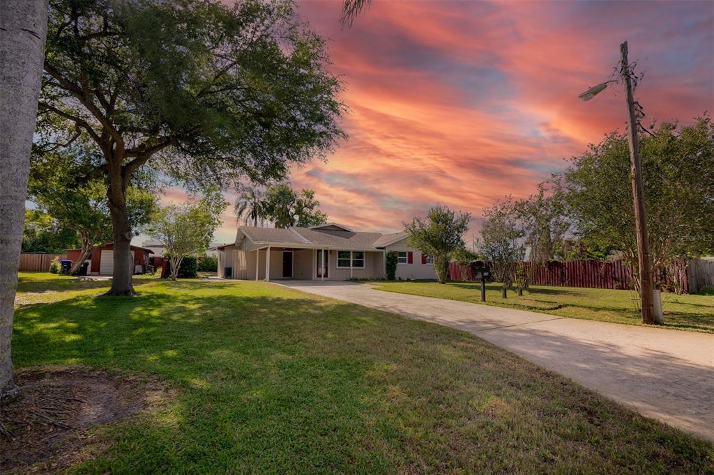A single-story house with a concrete driveway and a large lawn under a sunset sky — 525 OLOLU DRIVE, WINTER PARK, FL