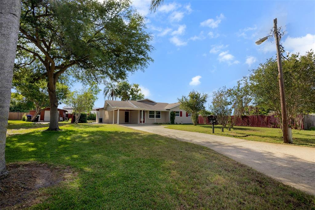A single-story house with a concrete driveway, a large tree, and a red fence — 525 OLOLU DRIVE, WINTER PARK, FL
