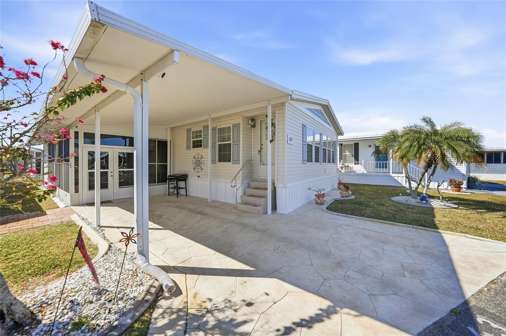 A manufactured home features a covered carport, a screened-in porch, and a concrete driveway — 10100 BURNT STORE ROAD UNIT 63, PUNTA GORDA, FL