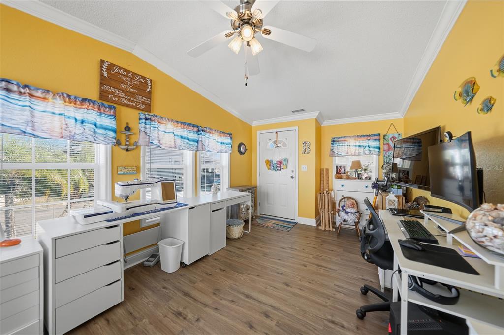 A bright yellow craft room features a sewing station, a computer desk, and wood-look flooring — 10100 BURNT STORE ROAD UNIT 63, PUNTA GORDA, FL