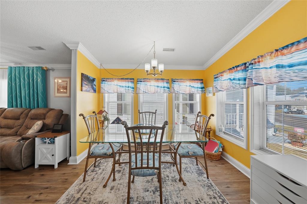 A dining room with yellow walls, a glass-top table, and a patterned area rug — 10100 BURNT STORE ROAD UNIT 63, PUNTA GORDA, FL