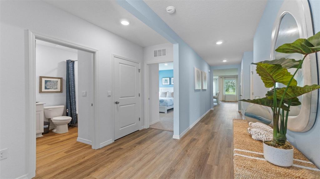 A hallway with light blue walls, wood-look flooring, and doorways leading to a bathroom and bedroom — 1332 FOUNTAIN VIEW STREET, ORMOND BEACH, FL