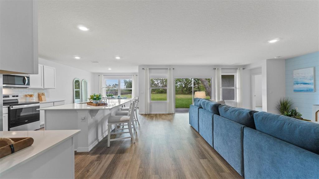 An open-concept kitchen and living area features white cabinetry, a large island, and blue seating — 1332 FOUNTAIN VIEW STREET, ORMOND BEACH, FL