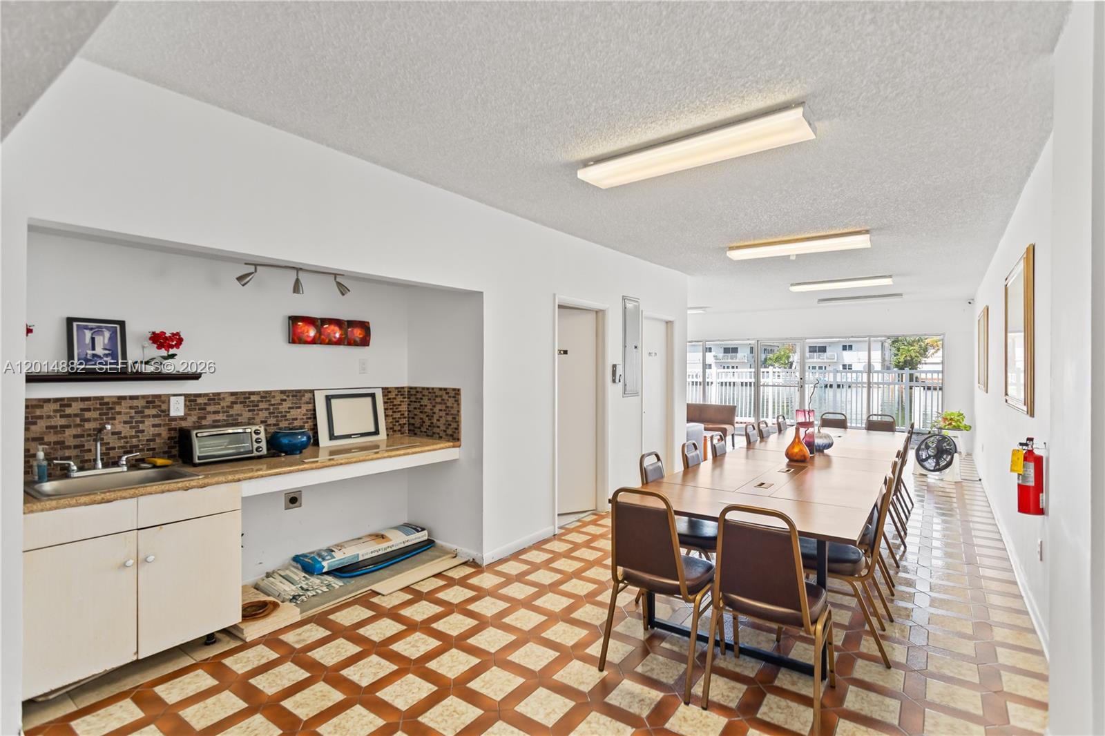 A community room features a kitchenette, a long dining table with chairs, and tiled floors — 8530 Byron Ave # 302, Miami Beach FL 33141, MIAMI BEACH, FL