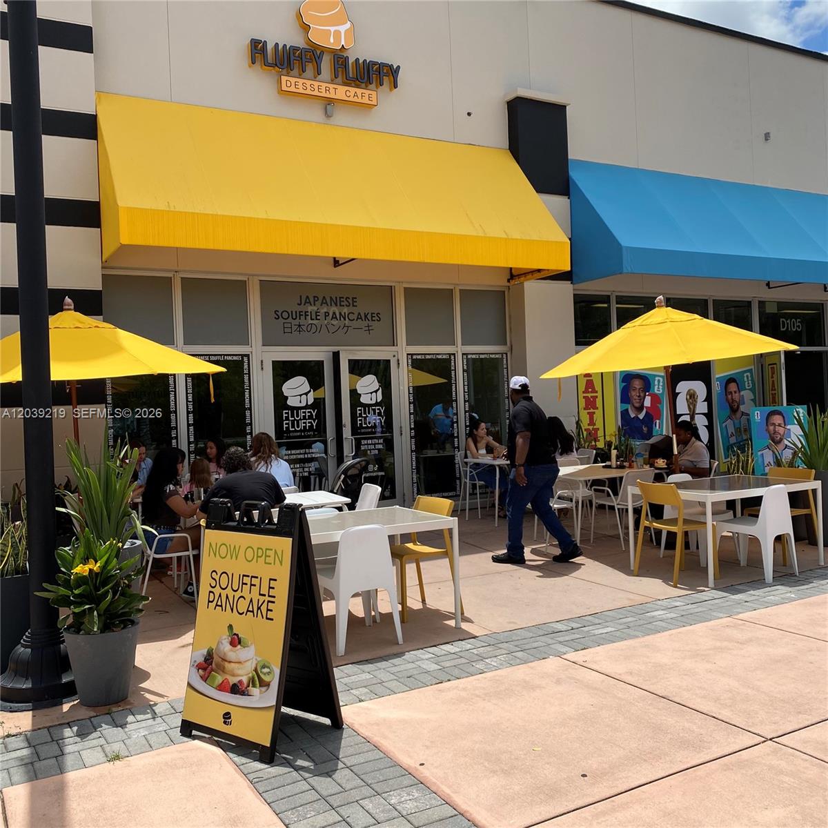 The exterior of a Fluffy Fluffy dessert cafe features yellow awnings and outdoor patio seating — 5241 NW 87th Ave D104, Doral FL 33178, DORAL, FL