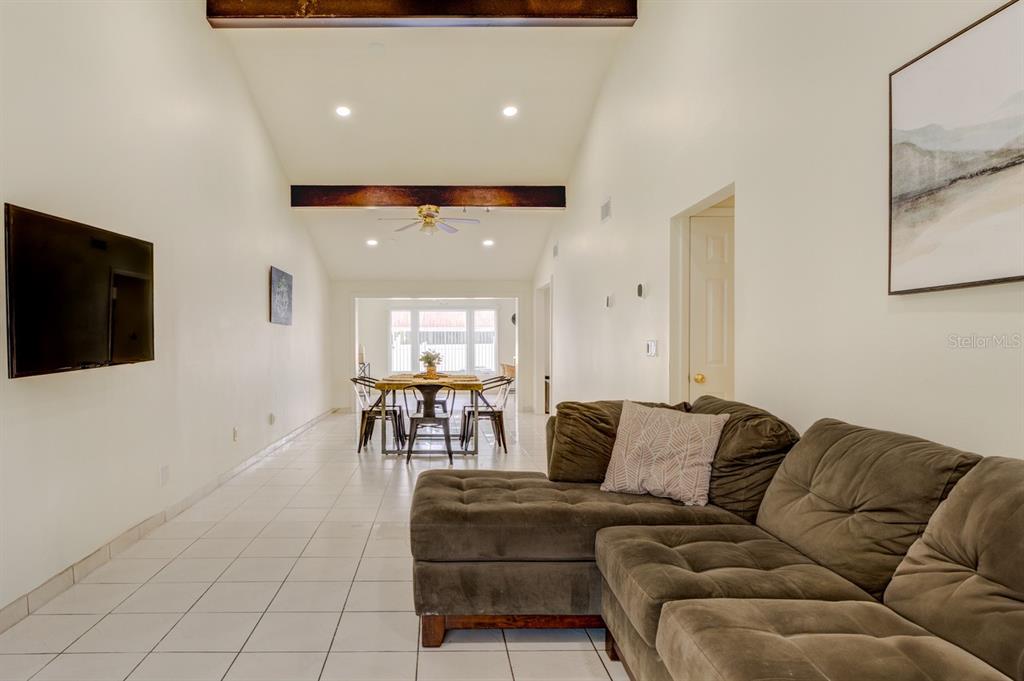 A living room with a sectional sofa, tiled floors, and a dining area beyond — 8541 BRIAR GROVE CIRCLE, TAMPA, FL