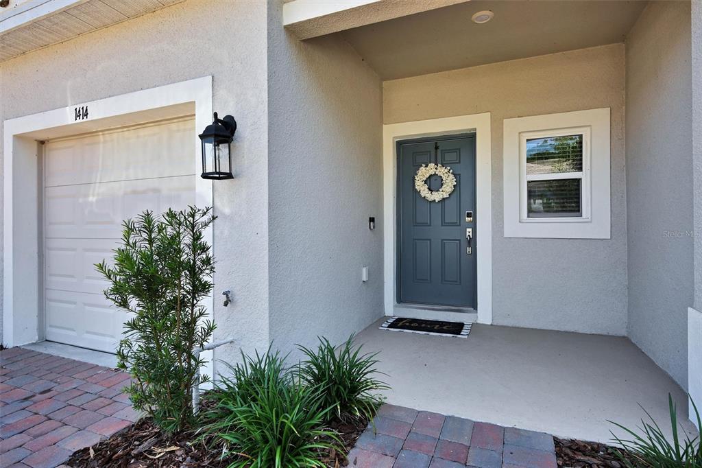 A gray front door with a wreath sits next to a garage and a window — 1414 ANCHOR BEND WAY, KISSIMMEE, FL