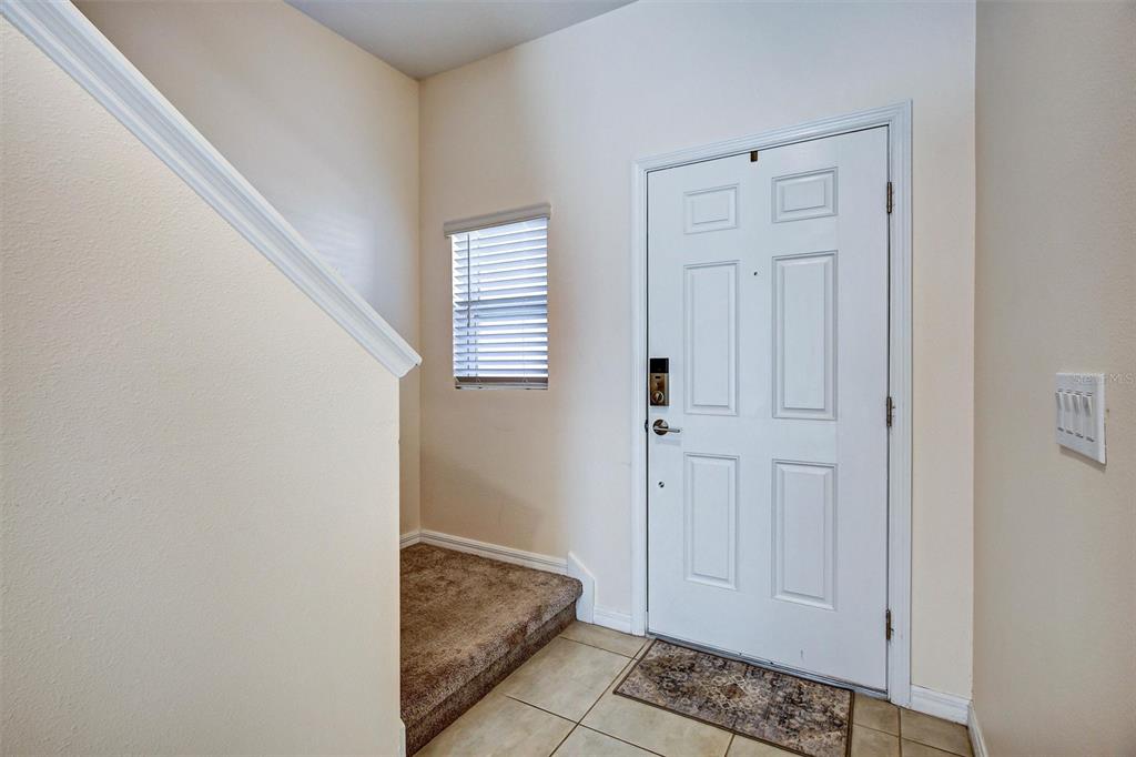 An entryway features a white front door, a carpeted staircase, and light-colored tile flooring — 1414 ANCHOR BEND WAY, KISSIMMEE, FL