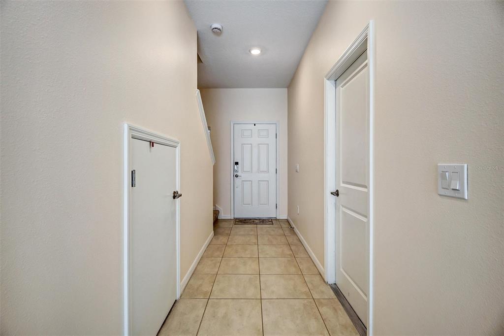 A tiled entryway features a front door, a small under-stair door, and a closet door — 1414 ANCHOR BEND WAY, KISSIMMEE, FL