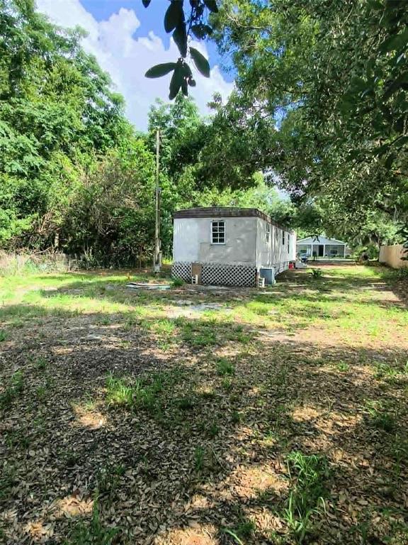 A mobile home sits on a grassy lot surrounded by trees — 2840 EATON AVENUE, LAKELAND, FL