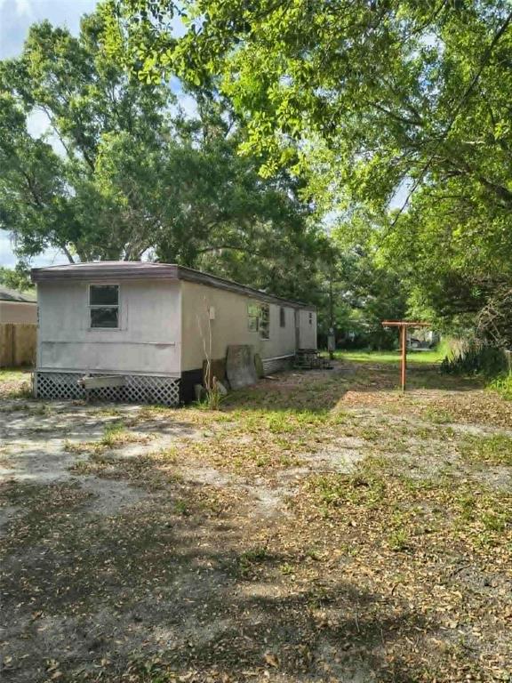 A single-wide mobile home sits on a dirt lot surrounded by mature trees — 2840 EATON AVENUE, LAKELAND, FL