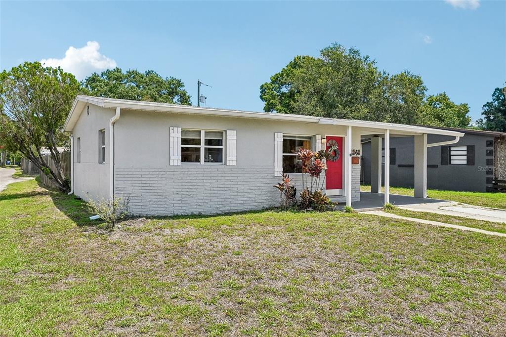 A single-story house with a gray exterior, a red front door, and a covered carport — 1547 56TH AVENUE N, ST PETERSBURG, FL
