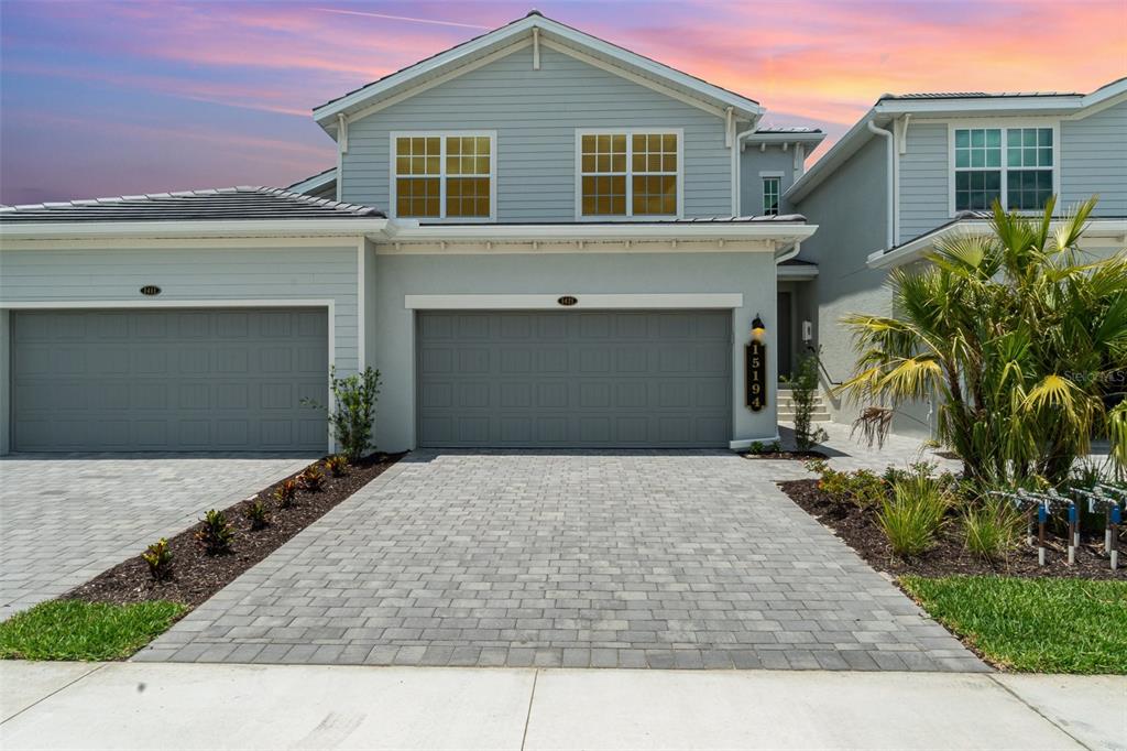 A two-story house exterior features a paved driveway, two garage doors, and light-colored siding — 15194 BLUFFTON LANE UNIT 1421, PUNTA GORDA, FL