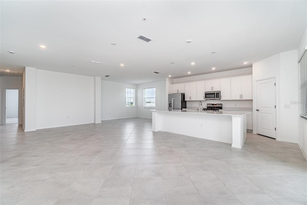 A spacious, open-concept kitchen and living area features white cabinetry, tile flooring, and recessed lighting — 15194 BLUFFTON LANE UNIT 1421, PUNTA GORDA, FL