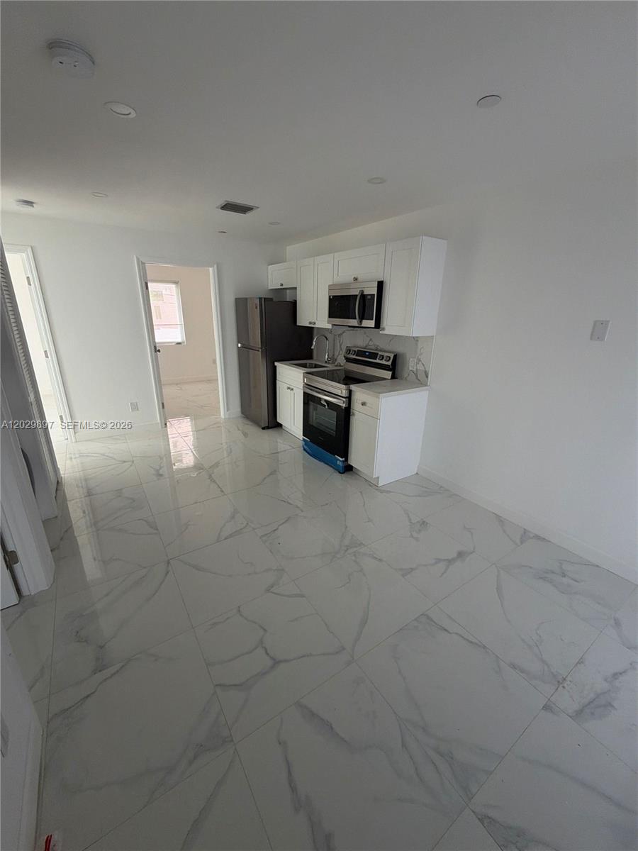 A kitchen features white cabinets, stainless steel appliances, and white marble-patterned tile flooring — 729 SW 3rd St # 2, Miami FL 33130, MIAMI, FL