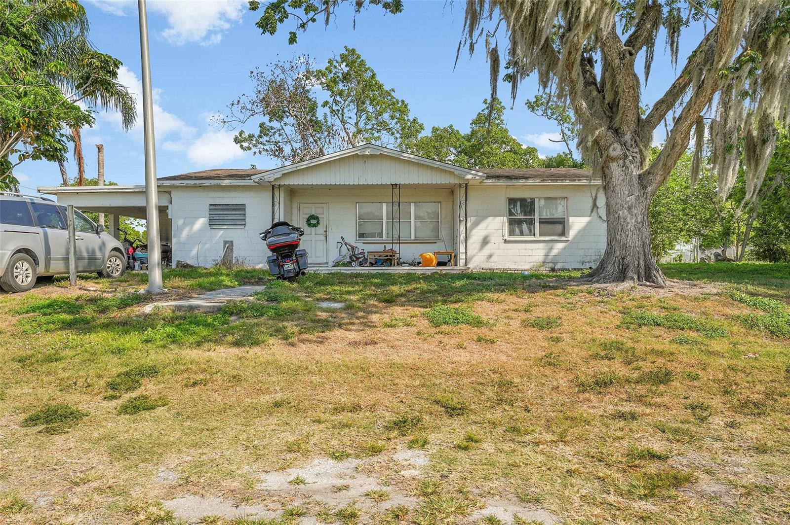 A single-story white concrete block house with a front porch and a large oak tree — 672 State Road 78, Okeechobee FL 34974, OKEECHOBEE, FL
