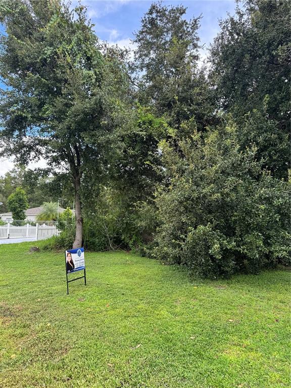 A grassy, wooded lot features a real estate sign in the foreground — 0 TIFFANY COURT, KISSIMMEE, FL