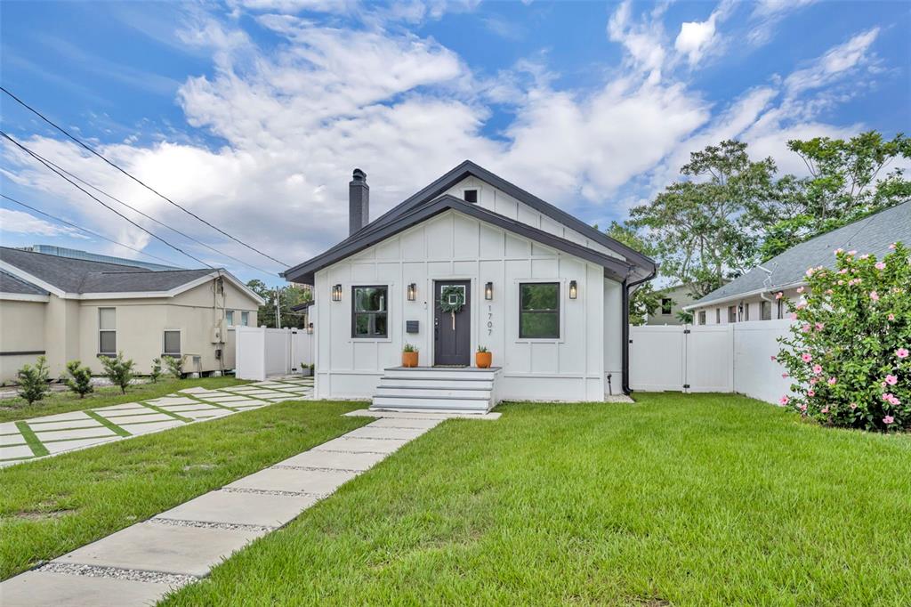 A white house with dark trim and a front walkway sits on a grassy lot — 1707 HARMON AVENUE, WINTER PARK, FL