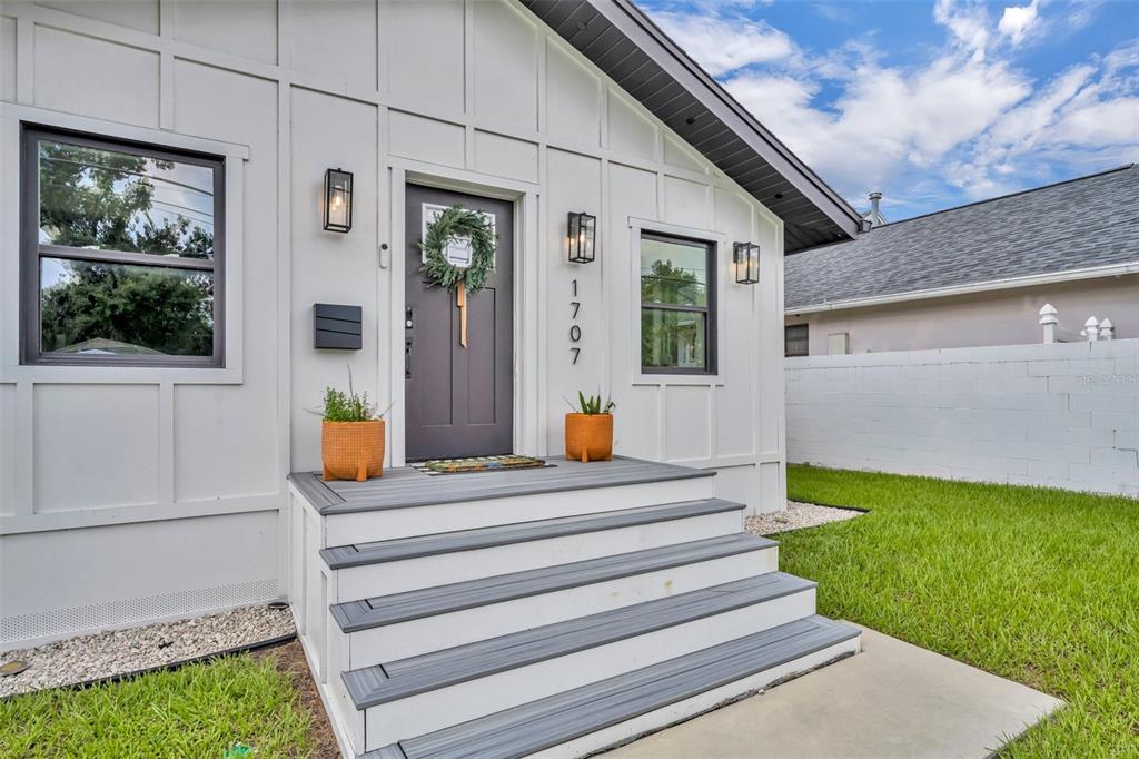 A white house exterior features a dark front door, gray steps, and two potted plants — 1707 HARMON AVENUE, WINTER PARK, FL