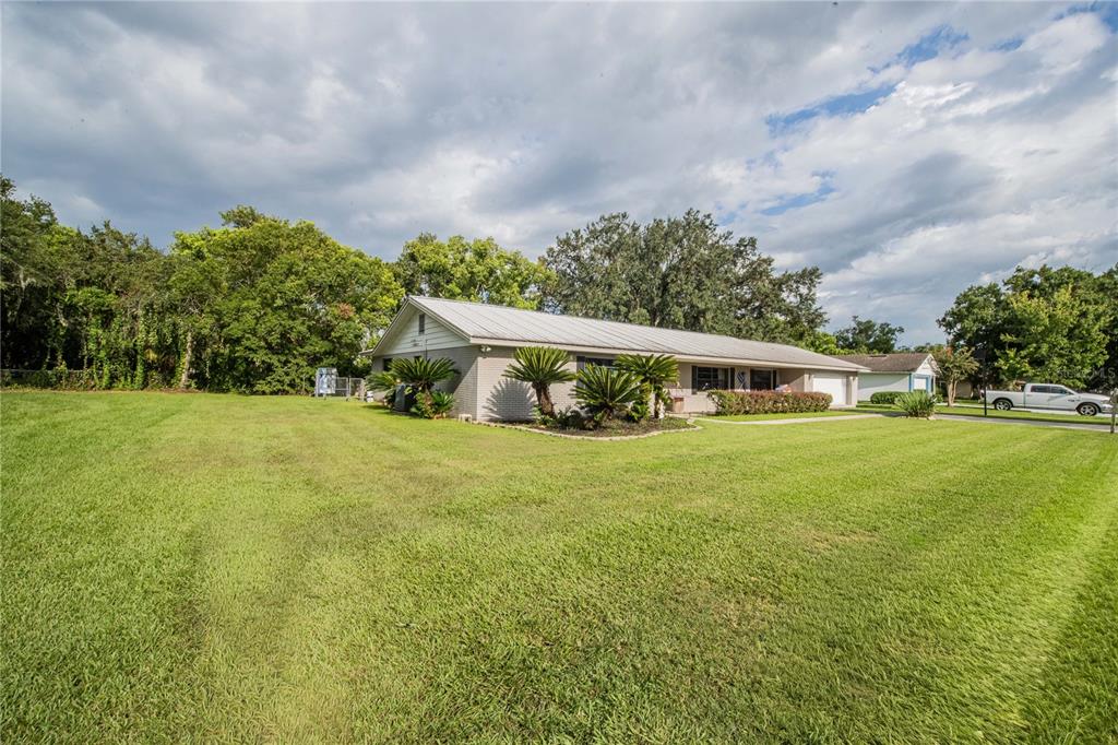 A single-story house with a metal roof and brick exterior sits on a large lawn — 5934 RIDGE DRIVE, LAKELAND, FL