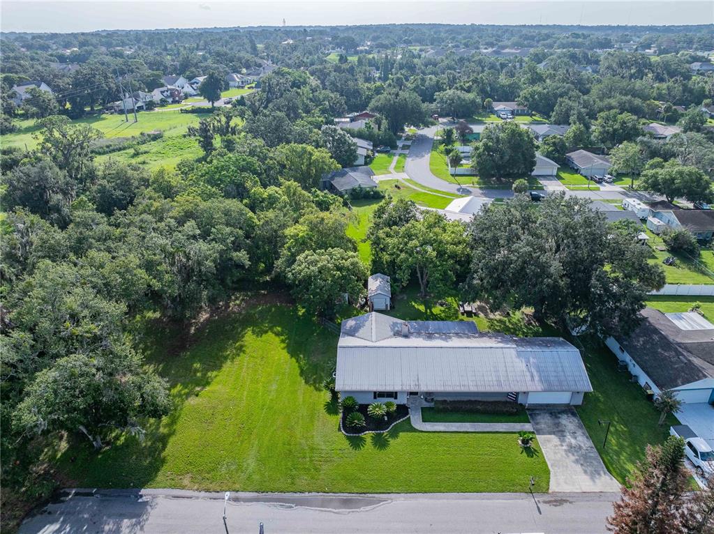 An aerial view shows a single-story house with a metal roof and a large lawn — 5934 RIDGE DRIVE, LAKELAND, FL